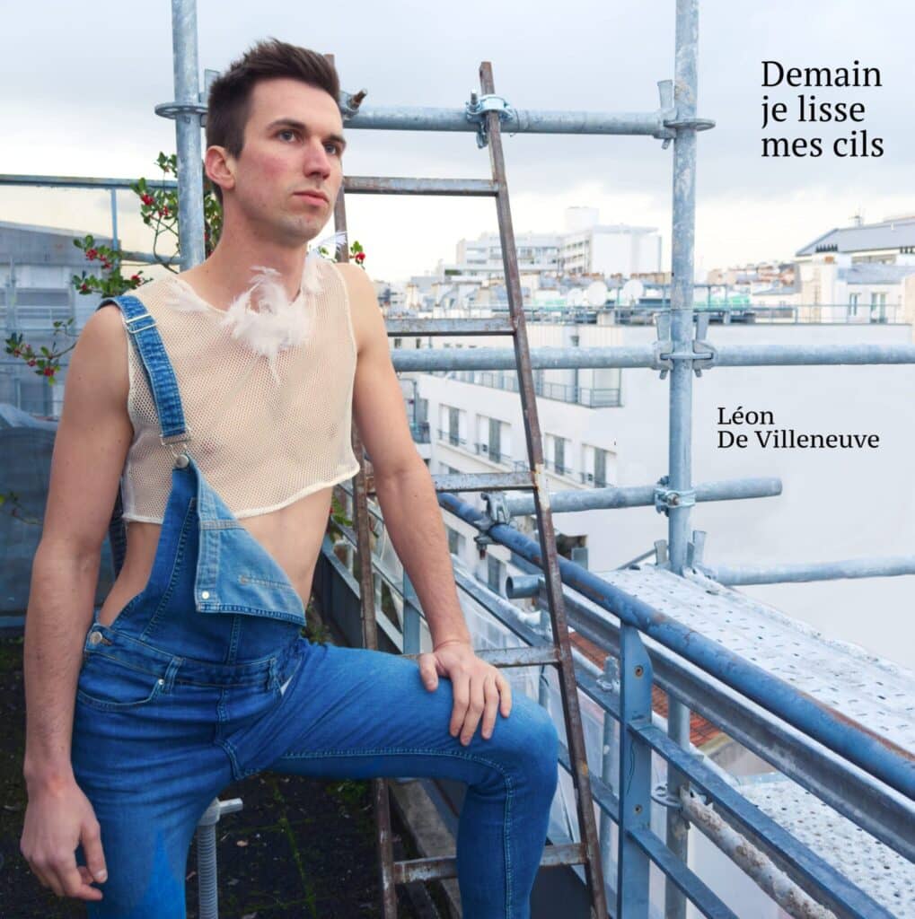 Pierre Villeneuve chanteur interprète en salopette et crop top à plume sur un toit avec échafaudage en arrière plan et ciel ouvert